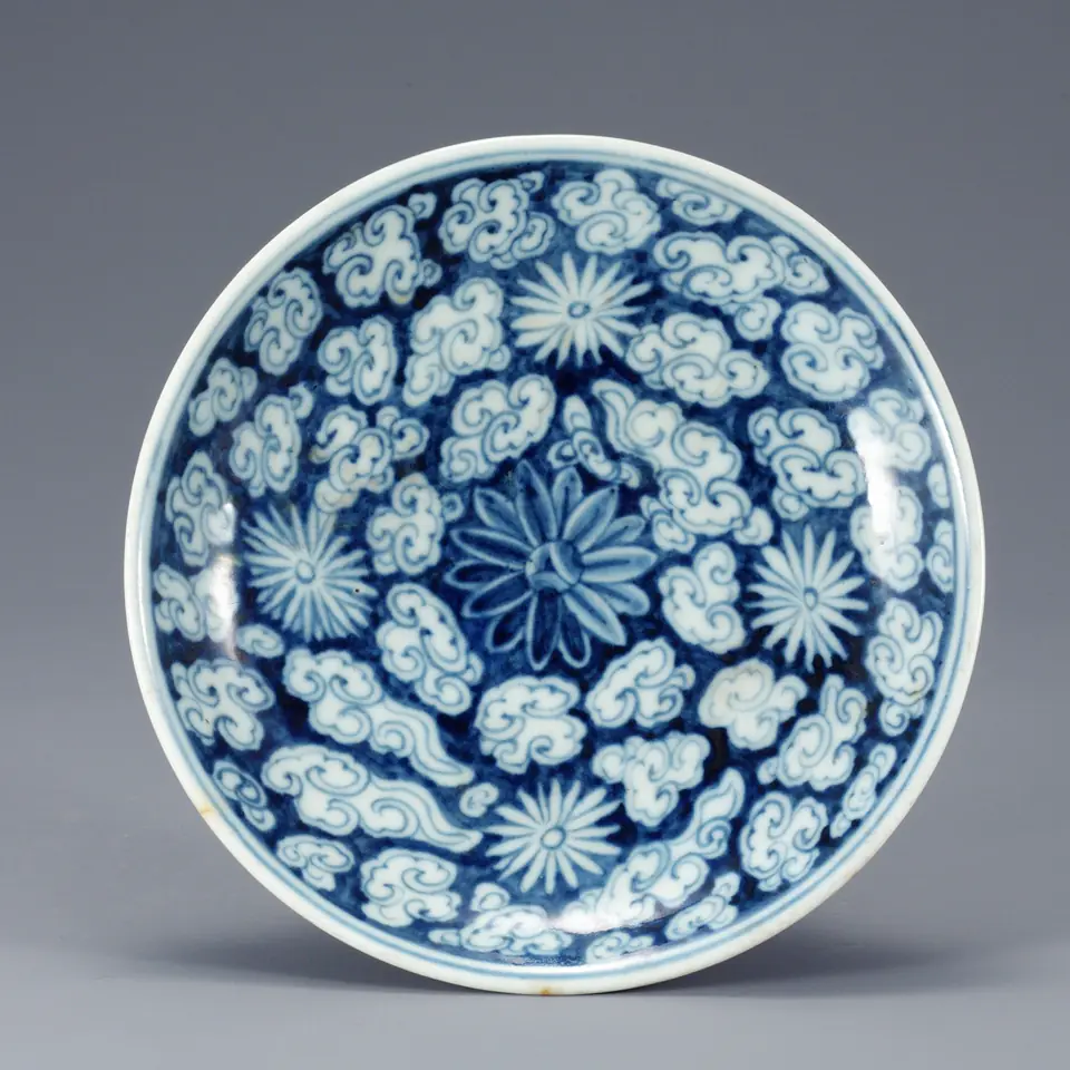 White porcelain plate densely painted with cobalt-blue clouds and a chrysanthemum